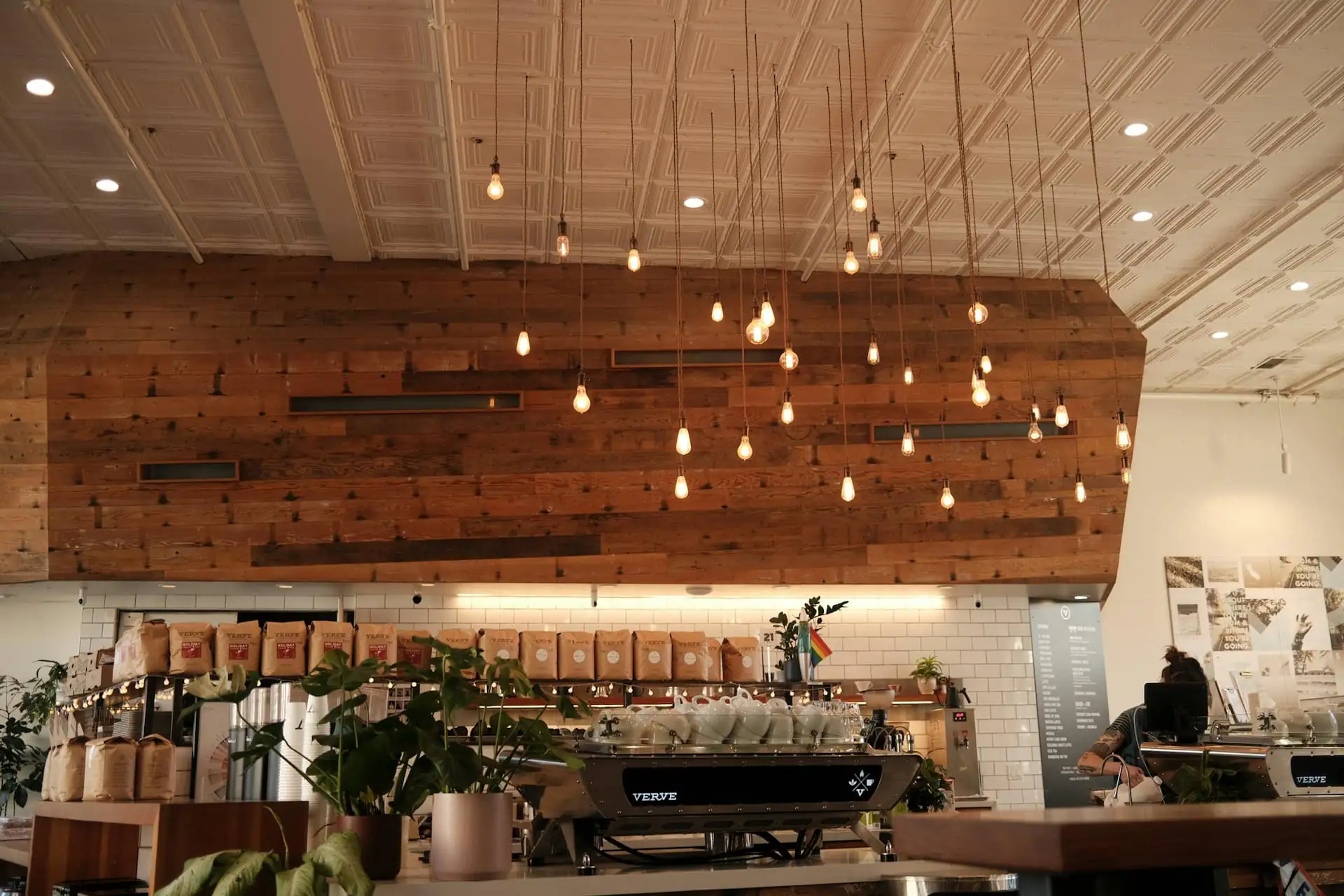 Café interior with tiled counter, pendant lights and timber seating